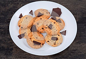 Chocolate chip cookies and broken chocolate pieces on white dish