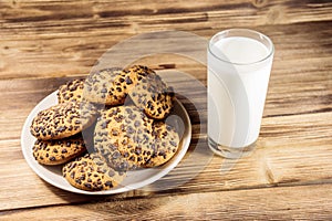 Chocolate chip cookies and glass of milk on wooden table