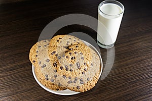 Chocolate chip cookies and glass of milk on wooden table