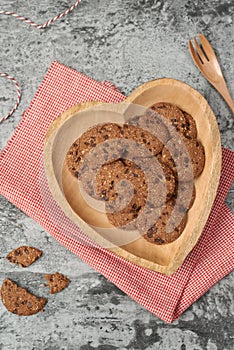 Chocolate chip cookies on heart-shape plate on grey stone background