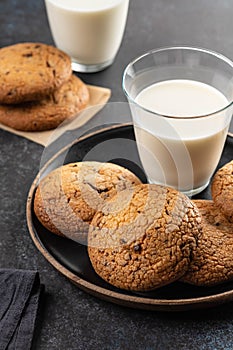 Chocolate chip cookies with milk on black table. Copy space.