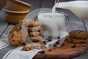 Chocolate chip cookies with milk on old wooden table