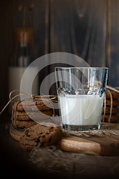 Chocolate chip cookies and milk on wooden background with vignette