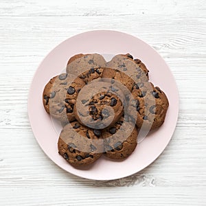 Chocolate chip cookies on a pink plate on a white wooden background. Flat lay, overhead