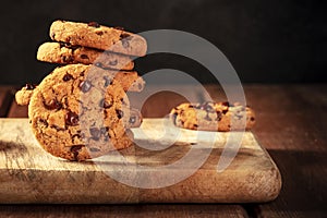 Chocolate chip cookies stack on a dark rustic wooden background