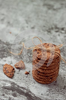 Chocolate chip cookies are stack and tied with twine on stone background