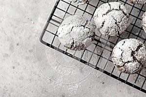 Chocolate chip cracked cookies. Metallic rack with fresh baked chocolate crinkle cookies in icing sugar on gray textured