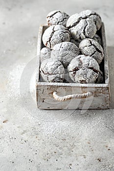 Chocolate chip cracked cookies. Wooden rustic box with fresh baked chocolate crinkle cookies in icing sugar on gray