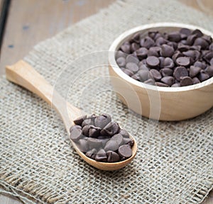 Chocolate chips in wooden spoon and bowl