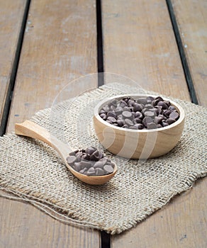Chocolate chips in wooden spoon and bowl