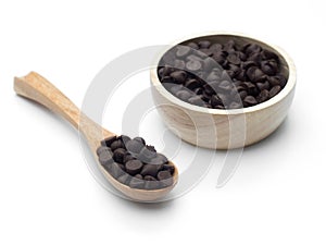 Chocolate chips in wooden spoon and bowl on white background