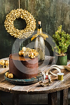 Chocolate christmas cake with gold decor champagne behind rustic style