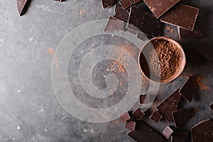 Chocolate chunks and cocoa powder. Chocolate bar pieces. A large bar of chocolate on gray abstract background.