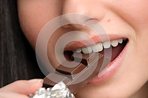 Chocolate - close-up of young woman bite piece