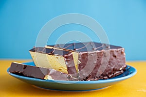 Chocolate coated milk mousse called `Ptasie Mleczko` on a blue plate. Delicious and sweet dessert.