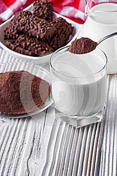 Chocolate cocoa milk powder on a white wooden rustic background