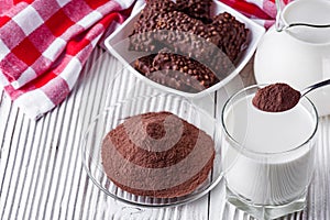 Chocolate cocoa milk powder on a white wooden rustic background