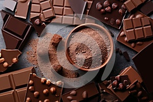 Los trozos de Chocolate con el cacao en polvo en un tazón y las bolas en la mesa de madera.