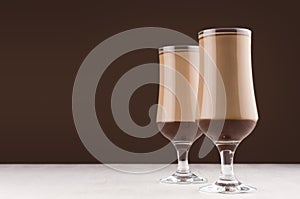 Chocolate and coffee dessert in two elegant transparent glass  in modern dark brown kitchen interior, copy space.