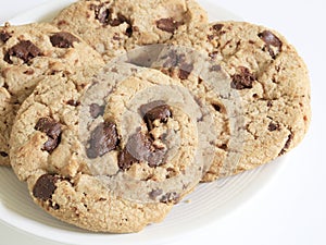 Chocolate cookies on brown cloth background. Chocolate chip cookies shot on white plate, closeup.