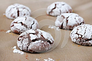 Chocolate cookies with cracks on baking paper and iolated on black. Cracked chocolate biscuits