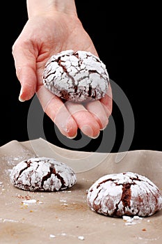 Chocolate cookies with cracks on baking paper and iolated on black. Cracked chocolate biscuits