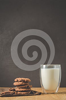 Chocolate cookies and glass of milk on wooden table/Chocolate cookies and glass of milk on wooden table and dark background with