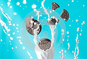 chocolate cookies in milk splash drops isolated over blue background. levitation trend photo