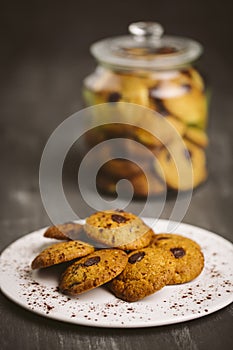 Chocolate cookies placed on a plate on a dark background.