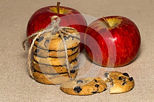 Chocolate cookies and a red apple on background burlap