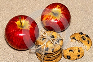 Chocolate cookies and a red apple on background burlap