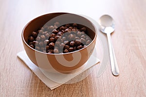 Chocolate corn balls in milk for Breakfast. Pouring milk with splashes of drops into a bowl of crispy Breakfast cereals rich in