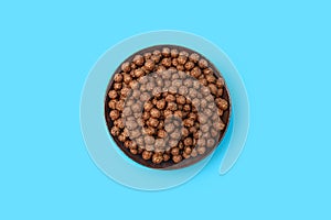 Chocolate corn flakes in a bowl on a blue isolated background in the center of the image