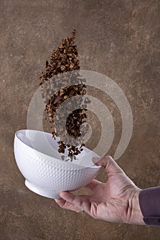Chocolate corn flakes falling to the white bowl on brown background. Levitation.