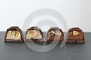 Chocolate corus candies in section with a white chocolate filling with hazelnuts peanuts praline ganache on a gray background with