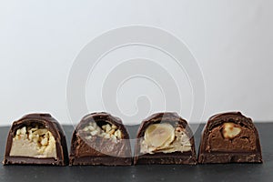 Chocolate corus candies in section with a white chocolate filling with hazelnuts peanuts praline ganache on a gray background with