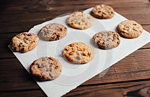 Čokoláda pokrytý sušienky stanoviť na pergamen v riadok. sušienky na drevený stôl von z rúra. selektívny 