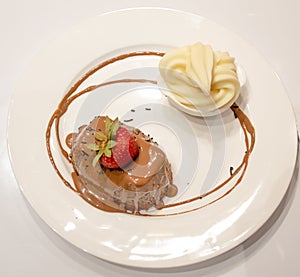 Chocolate cream cake with straberry, and vanilla icecream, white plate
