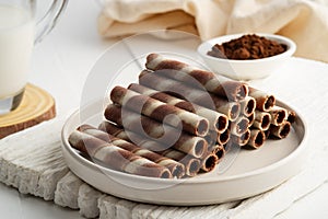 Chocolate cream flavour wafers sticks or wafer rolls in white plate. photo