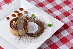 Chocolate creme brulee with cocoa powder, walnuts and mint leaf. Traditional French vanilla cream dessert.