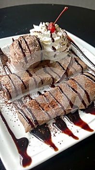 Chocolate crepe served with ice cream and whipping cream