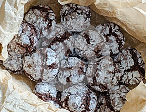 Chocolate crinkle cookies with powdered sugar icing. Cracked chocolate biscuits on paper background. close up. top view