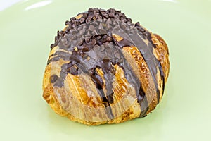 Chocolate croissant on green plate isolated on white background