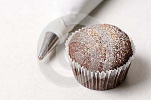 Chocolate cup cake with piping bag on the white marble background