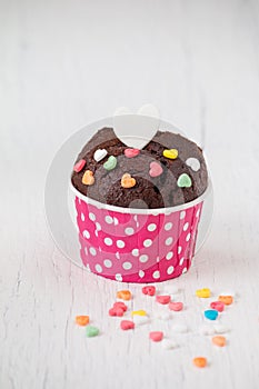 Chocolate cupcake with heart candy on white wooden table