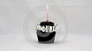 Chocolate cupcake with a pink candle burning on top