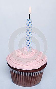 Chocolate cupcake with pink frosting and candle
