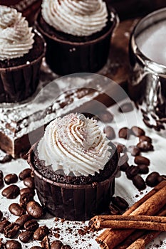Chocolate cupcake on a table among coffee beans and cinnamon