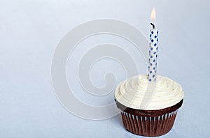 Chocolate cupcake with vanilla frosting and candle