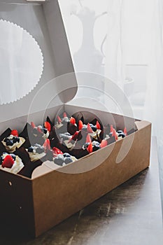 Chocolate cupcakes with berries in craft box.